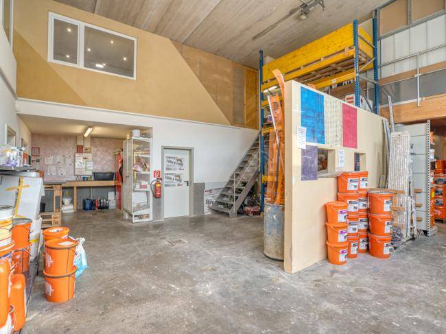 Gewerblicher Innenraum mit Treppe zum Obergeschoss und Arbeitsbereich, Betonboden.