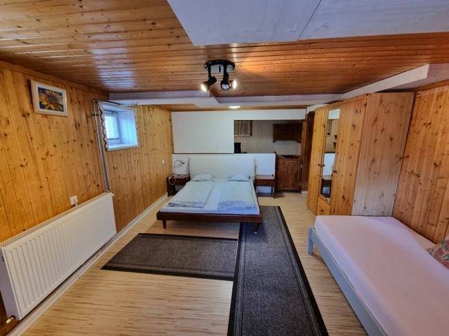 Schlafzimmer mit Holzvertäfelung an Wänden und Decke, Doppelbett und Einzelbett.
