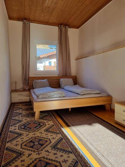 Schlafzimmer mit Doppelbett, gemustertem Teppich und Fenster mit Blick auf die Berge.