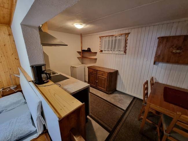 Rustikale Küchenzeile mit Holzelementen, Kochfeld und Esstisch in einem gemütlichen Raum.