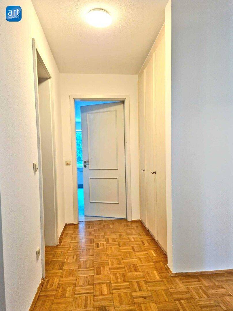 Heller Flur mit Parkettboden und integrierten Einbauschränken.