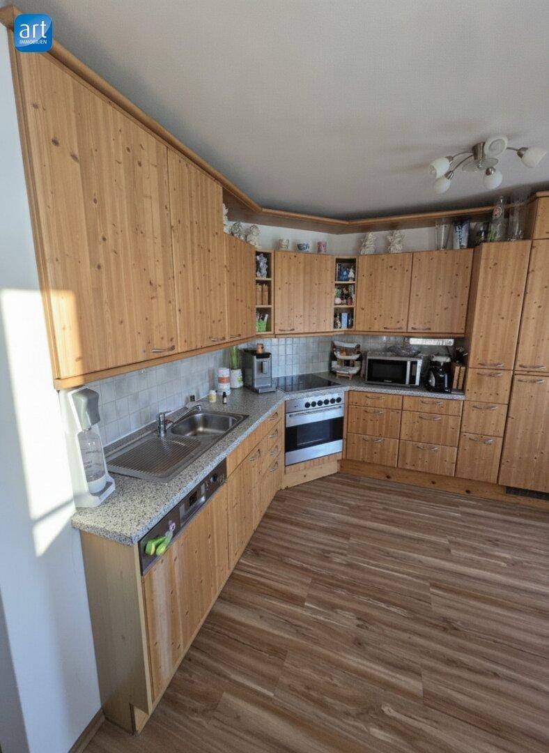 Traditionelle Holzküche mit Einbauschränken, Spüle und integrierten Küchengeräten.