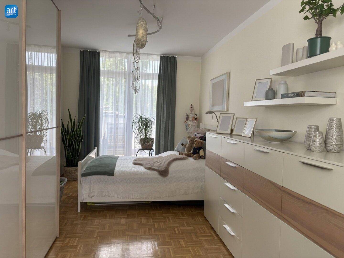 Schlafzimmer mit Parkettboden, Doppelbett und Zugang zu einem Balkon oder einer Terrasse.