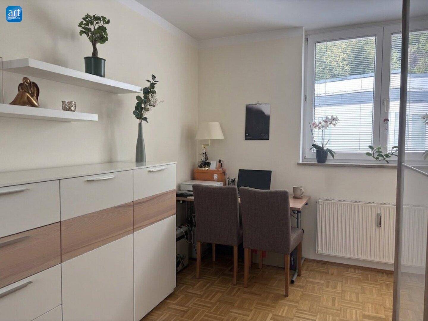Helles Arbeitszimmer mit Parkettboden, Schreibtisch und Regalen, ideal für Home-Office-Tätigkeiten.