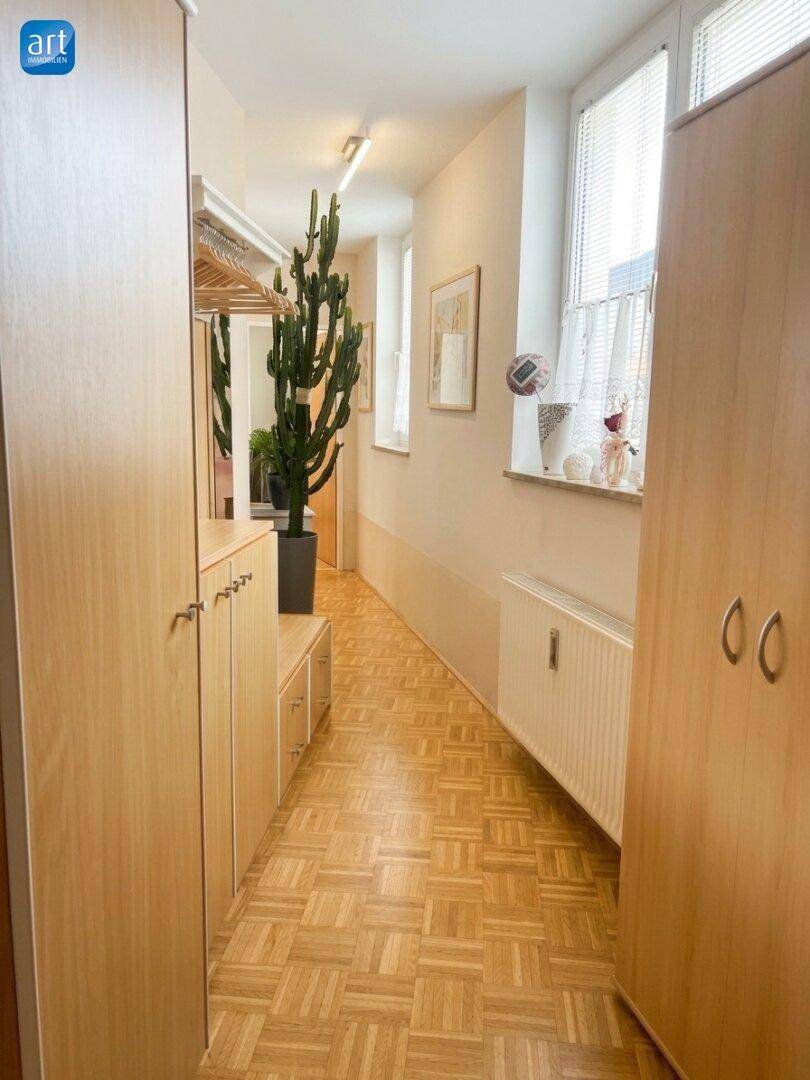 Heller Flur mit Einbauschränken, Parkettboden und Fenster für zusätzliche Belichtung des Raumes.