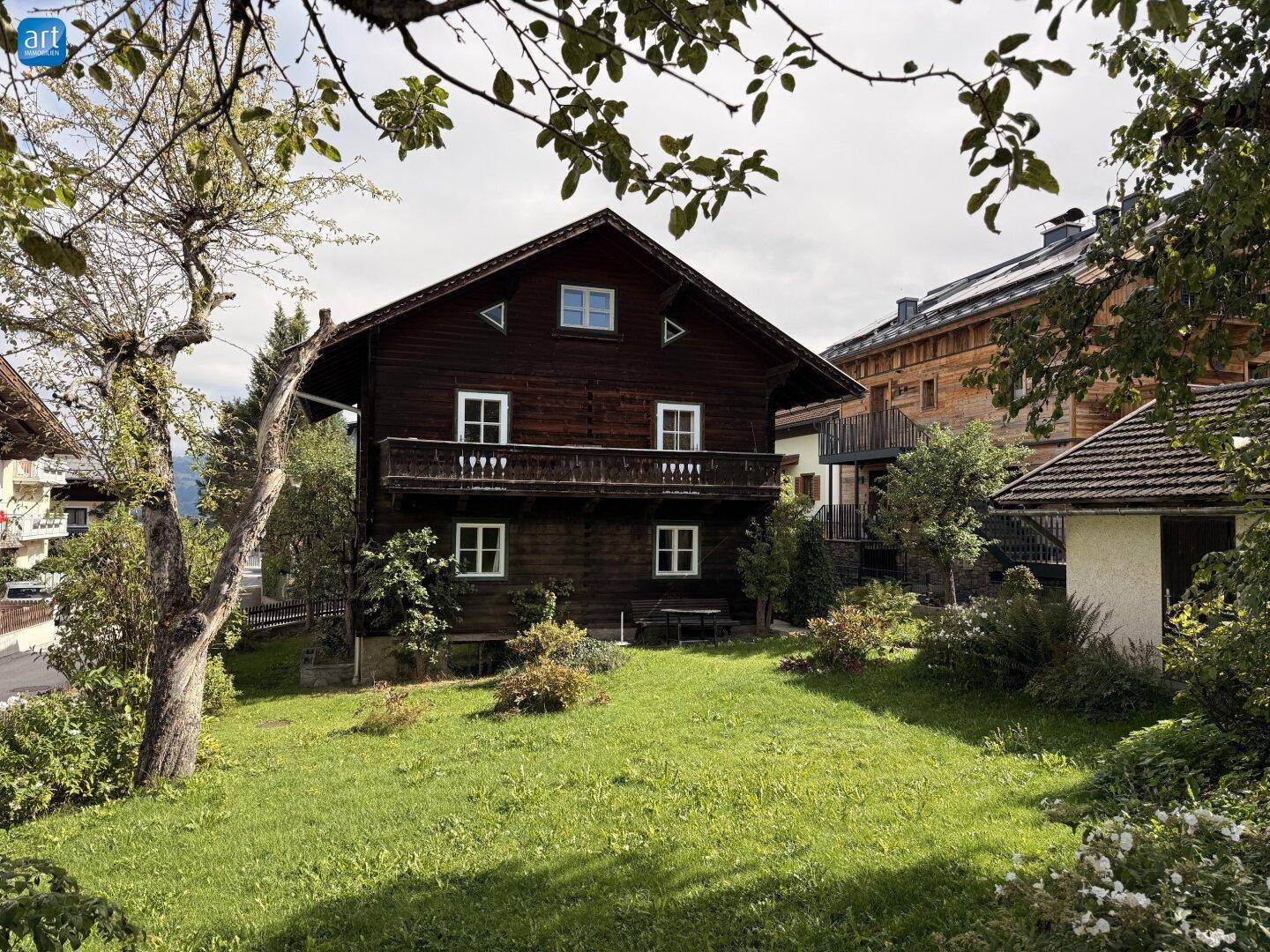 Rückansicht des Holzhauses mit Balkon und gepflegtem Gartenbereich.