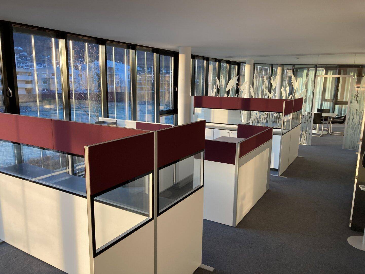 Offener Bürobereich mit modularen Arbeitsplätzen, großen Fenstern und viel Tageslicht.