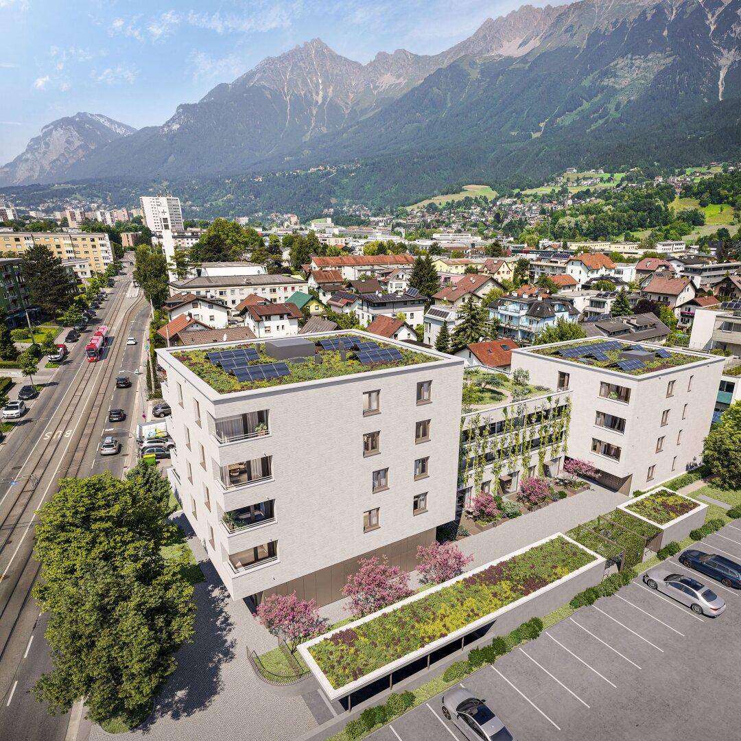 Panoramablick auf moderne Wohngebäude mit Gründächern, umgeben von Natur und Bergen.