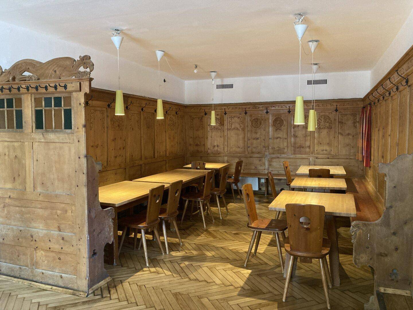 Geräumiger traditioneller Gastraum mit vielen Holztischen, Bänken und charakteristischer Holzvertäfelung.