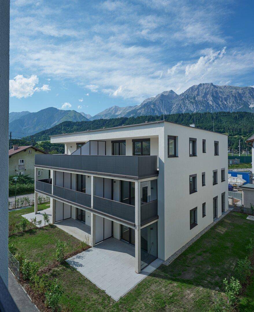 Modernes Wohngebäude mit großzügigen Balkonen und Blick auf die umliegende Berglandschaft.