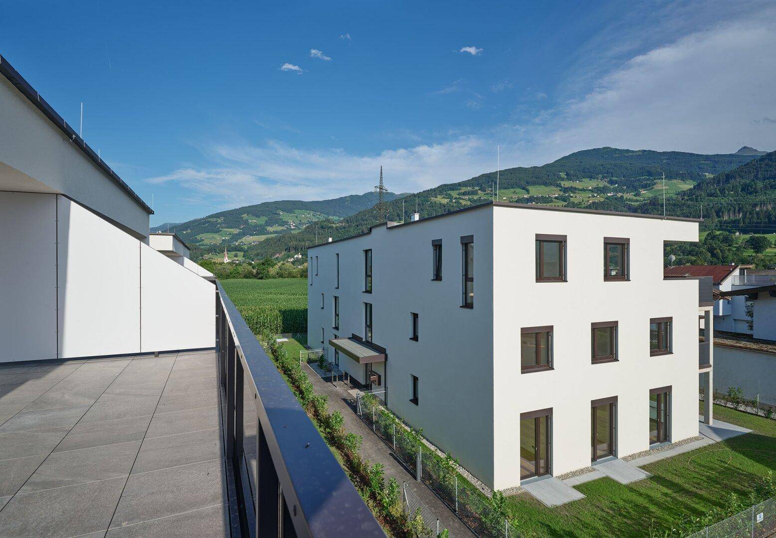 Seitenansicht eines modernen Gebäudes mit Flachdach und weitem Blick über die grüne Landschaft.