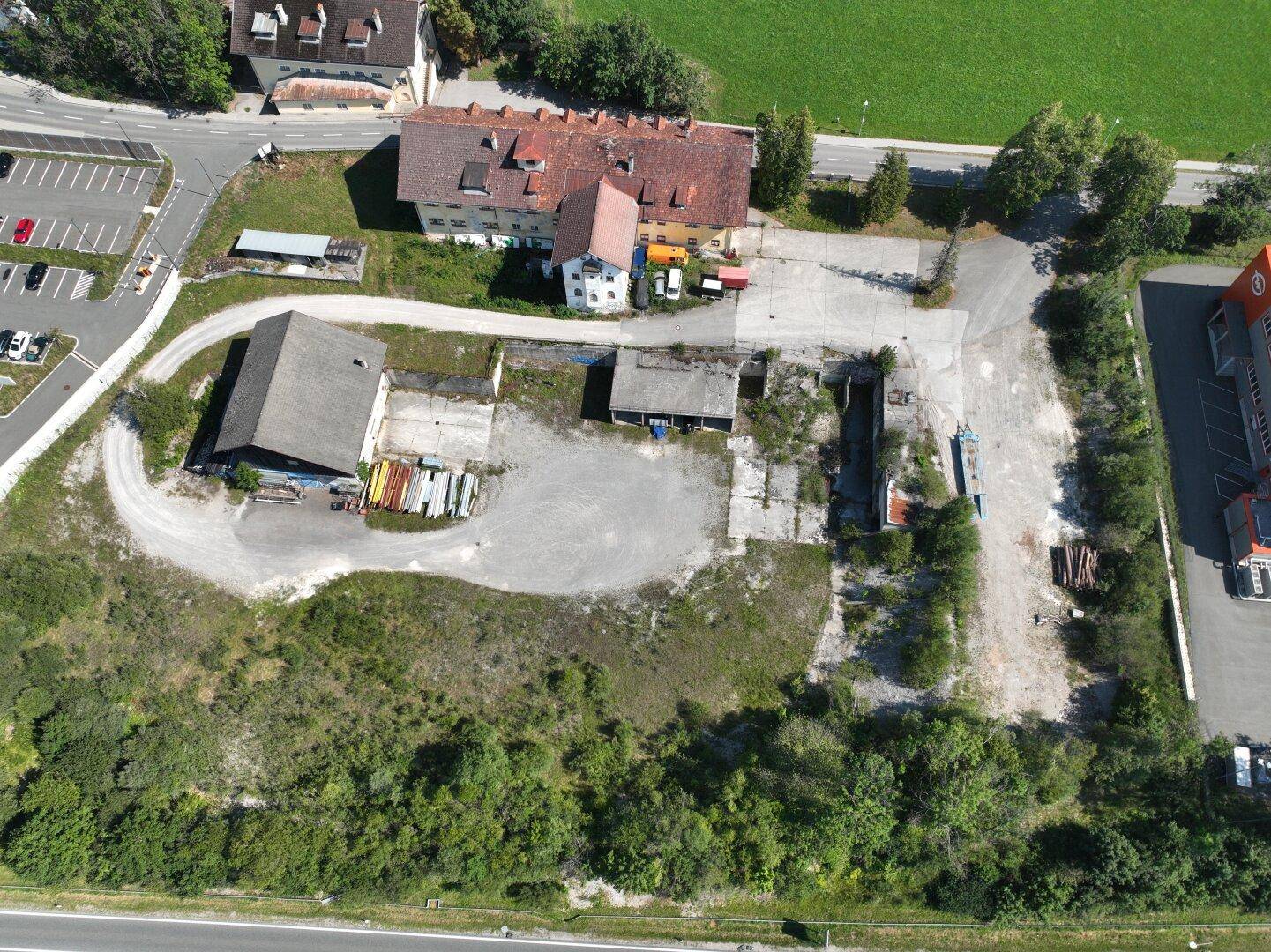 Übersicht aus der Vogelperspektive zeigt ein großes Grundstück mit Gebäuden, Freiflächen und angrenzender Natur.