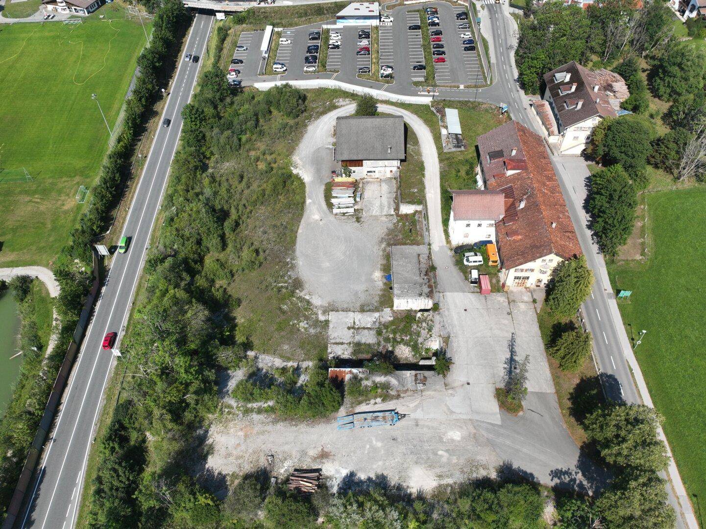 Luftbild des Anwesens mit mehreren Gebäuden, Freiflächen und einem großen Parkplatz in der Nähe.