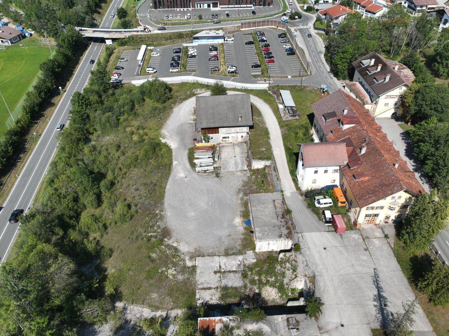 Übersichtsaufnahme aus der Luft zeigt das Grundstück mit Gebäuden, unbefestigten Wegen und einem angrenzenden Parkplatz.