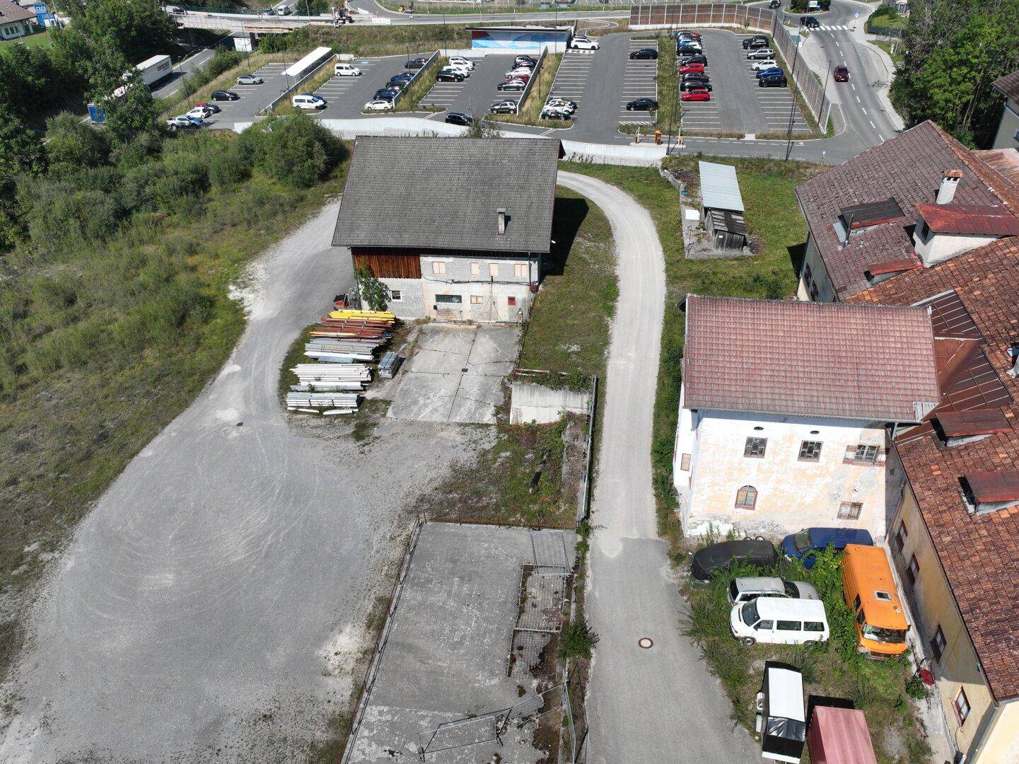 Luftbild zeigt ein Scheunengebäude und ein älteres Wohnhaus mit Ziegeldach, umgeben von Freiflächen und Fahrzeugen.