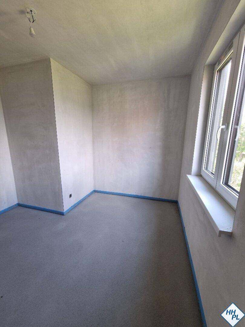 Unfertiger Raum mit Estrichboden und einem Fenster, bereit für den weiteren Ausbau.