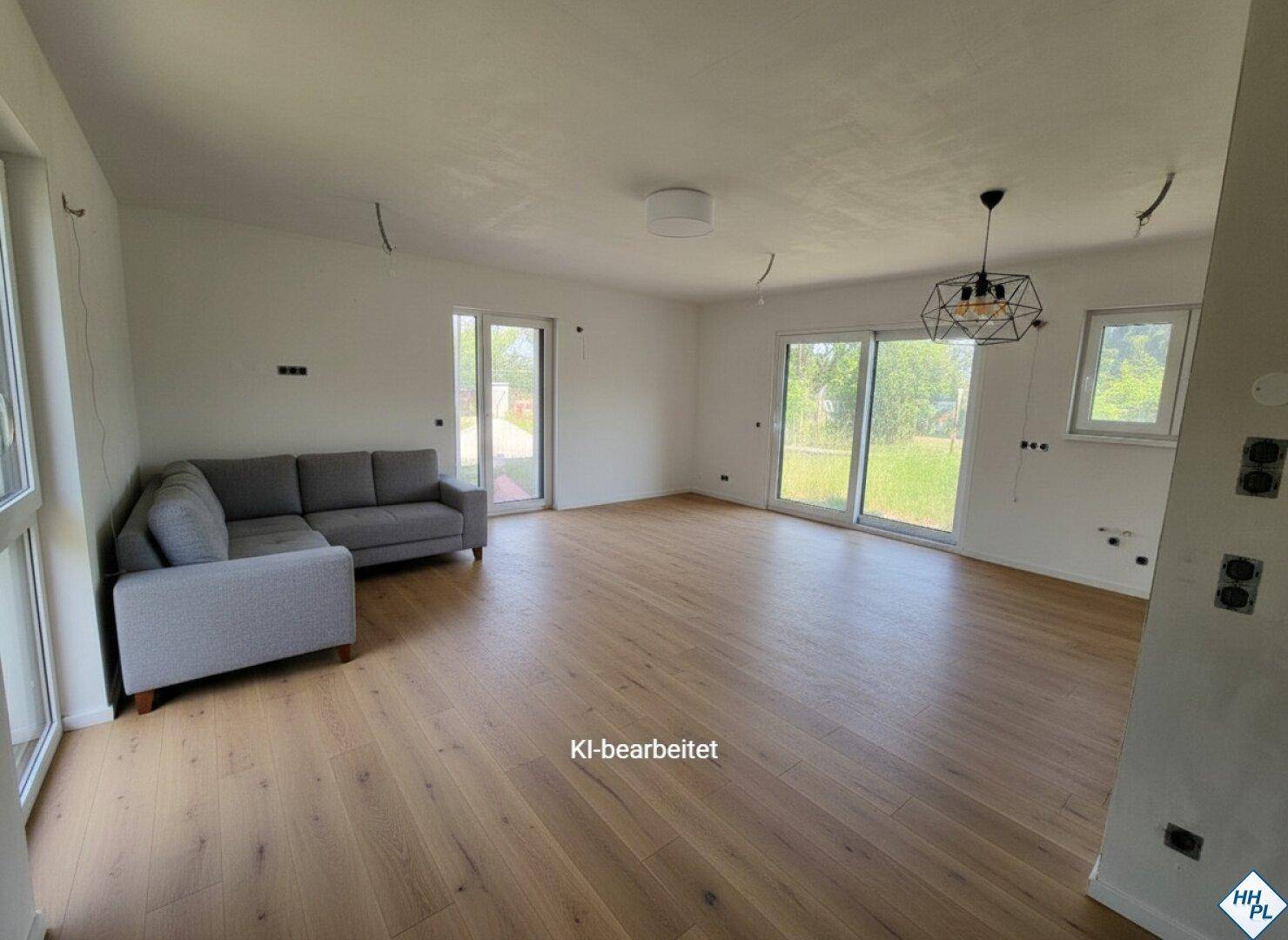 Helles Wohnzimmer mit modernem Holzboden, grauer Couch und Zugang zum Garten.