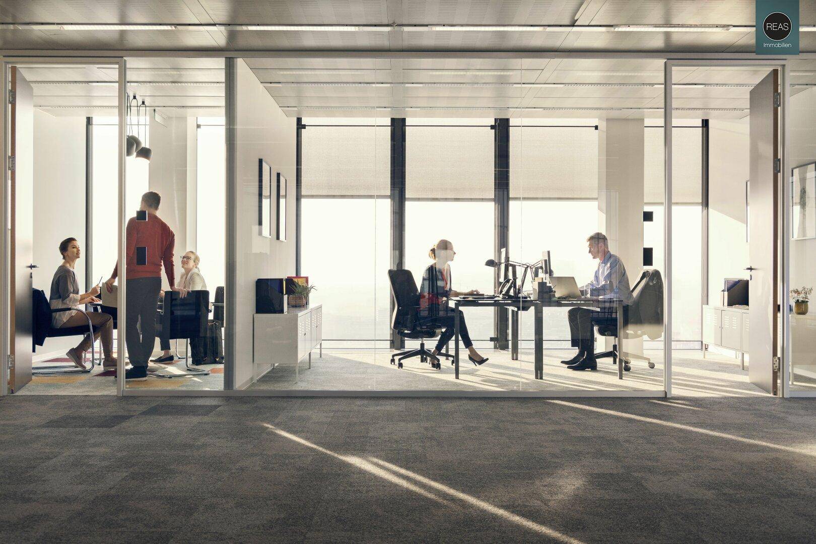 Großzügiges Büro mit mehreren Arbeitsbereichen, Glaswänden und viel Tageslicht.
