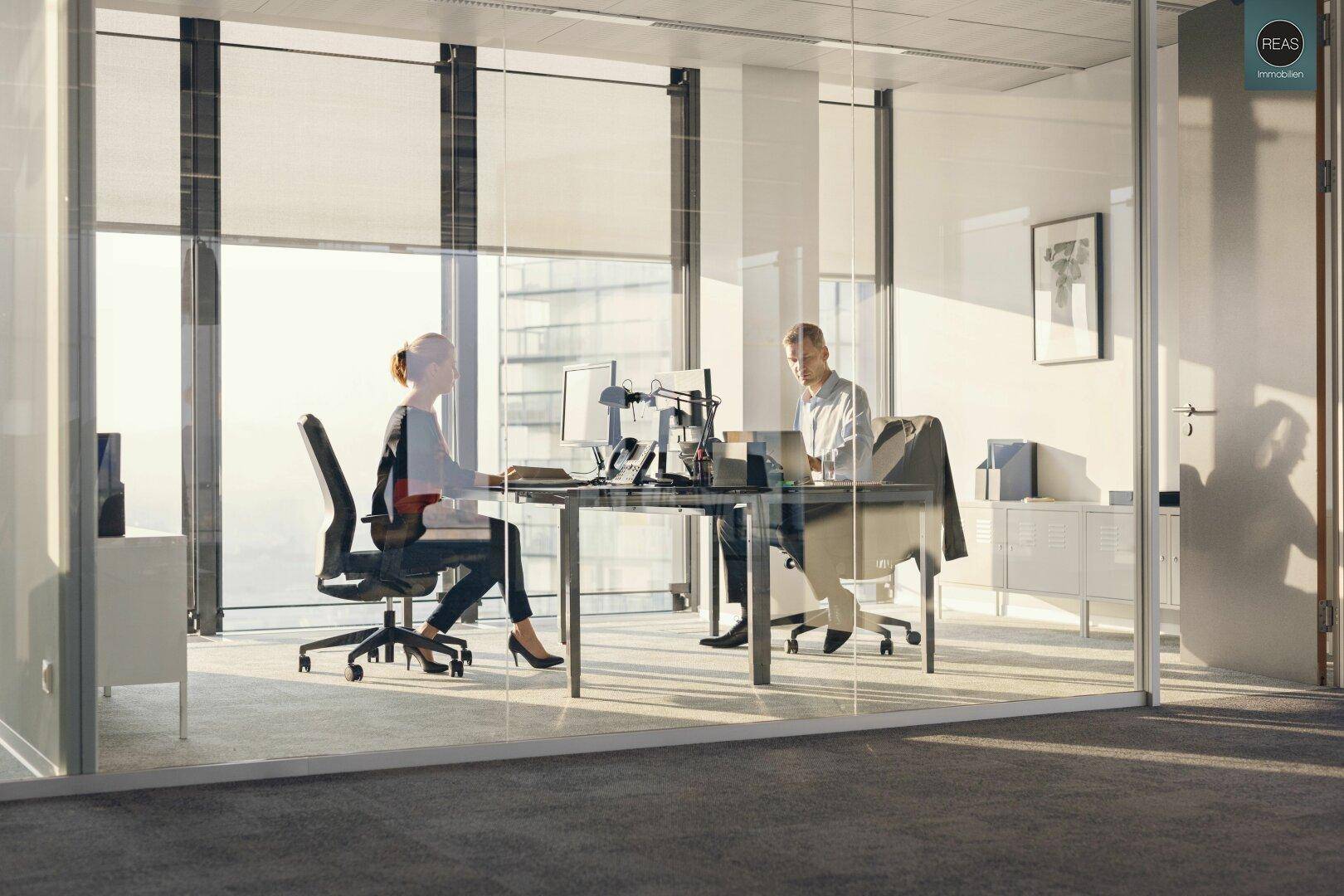 Moderner Arbeitsplatz in einem Büro mit Glaswänden und weitem Blick nach draußen.