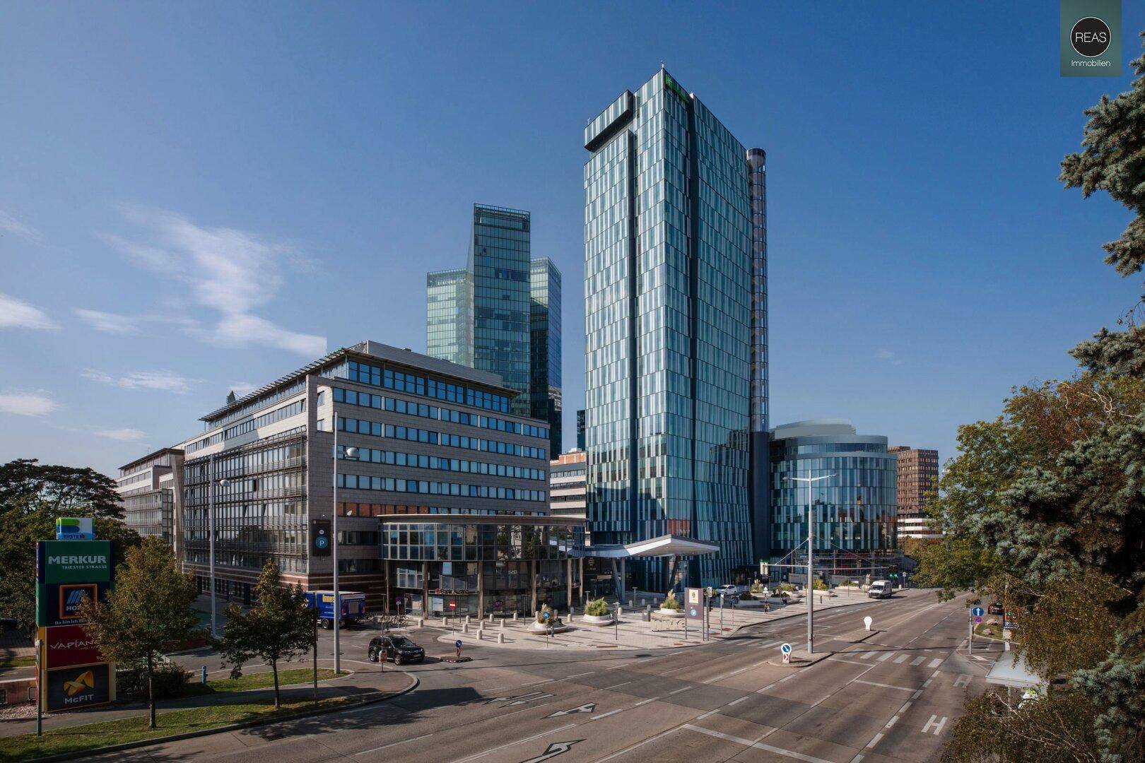 Moderne Bürogebäude mit Glasfassaden in einer städtischen Umgebung unter blauem Himmel.