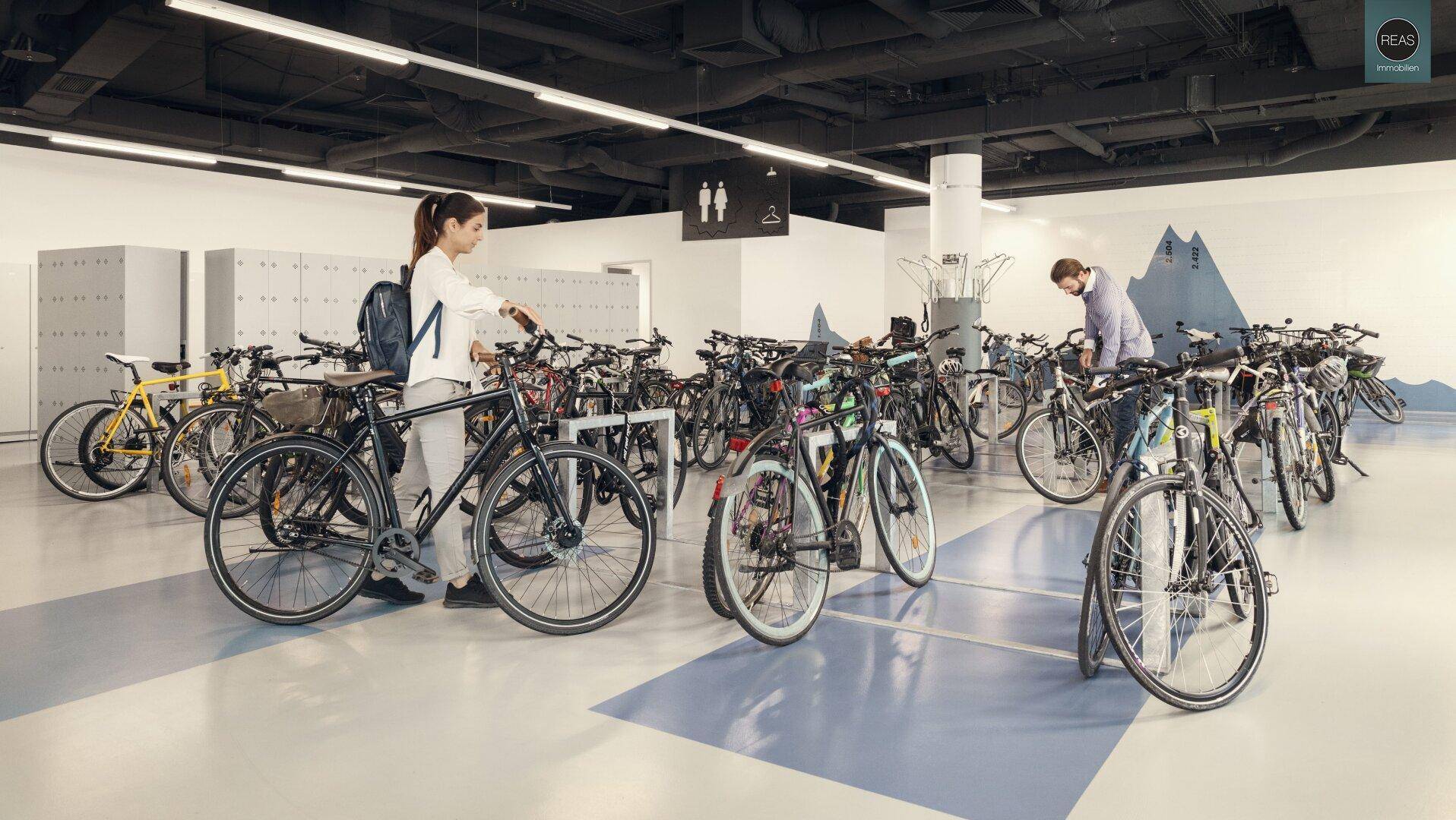 Großer Fahrradraum mit vielen Fahrrädern und Spinden im Hintergrund.