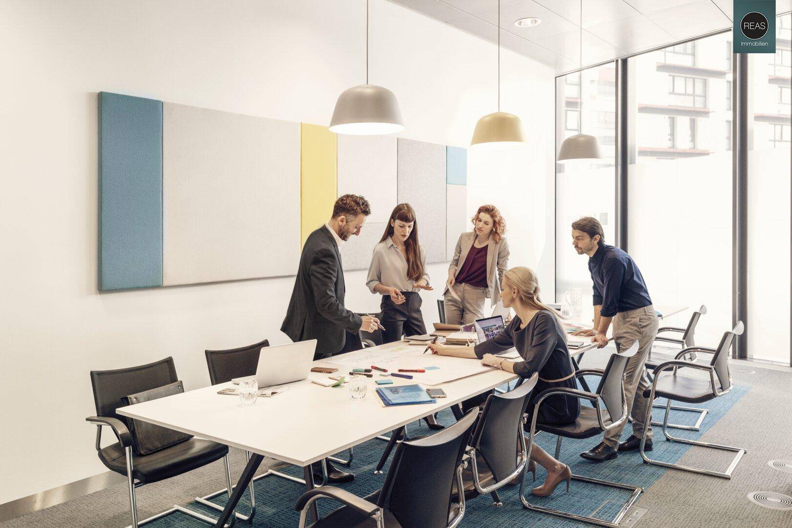 Modernes Besprechungszimmer mit Team, das an einem großen Tisch zusammenarbeitet.