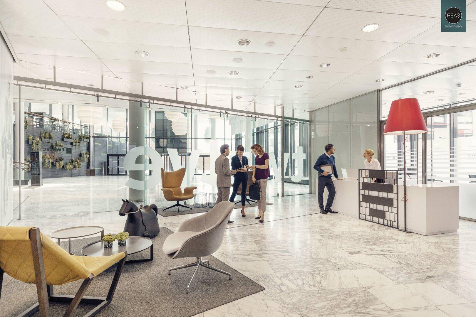 Elegantes Foyer mit Rezeption, Sitzgelegenheiten und großen Glasfronten.