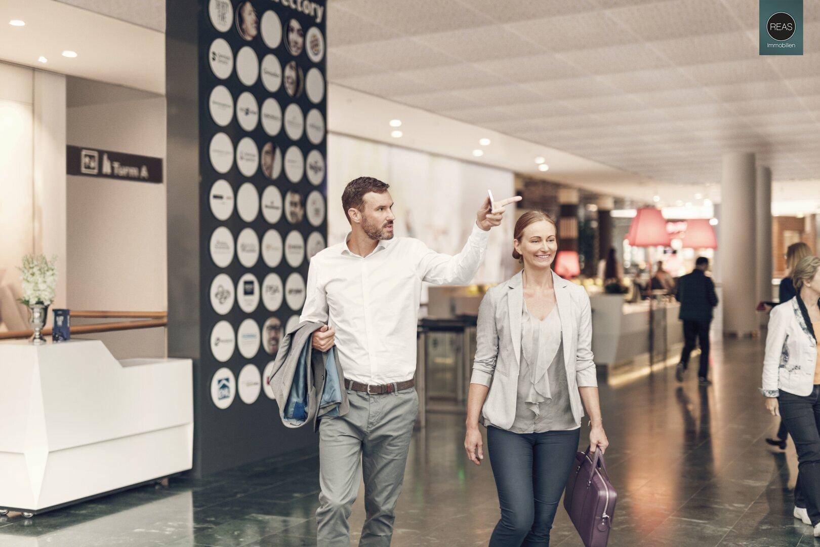 Modernes Foyer mit Personen, die sich orientieren, und einem digitalen Verzeichnis.