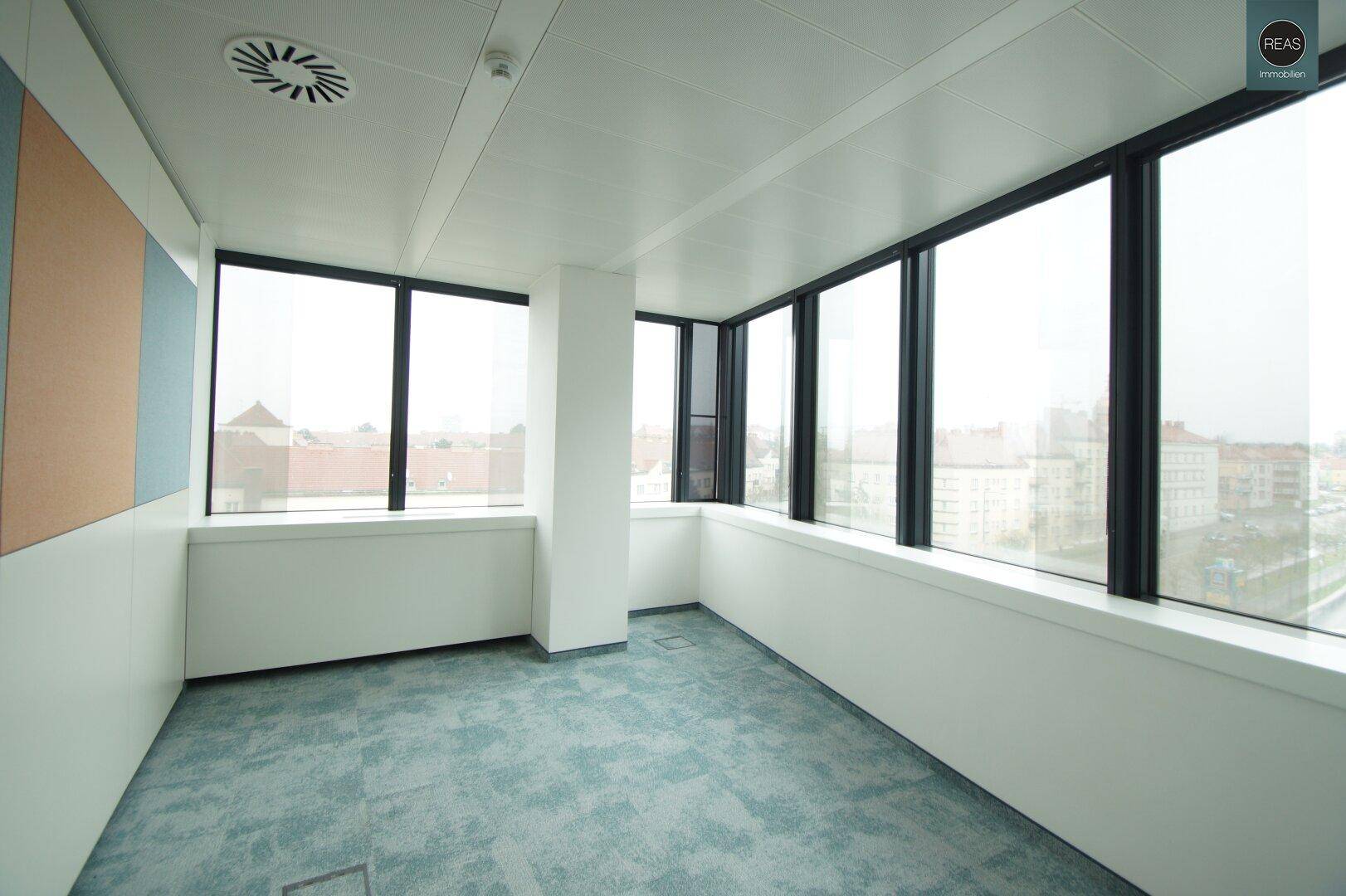 Helles Einzelbüro mit Teppichboden und großen Fenstern, bietet eine ruhige Arbeitsumgebung.