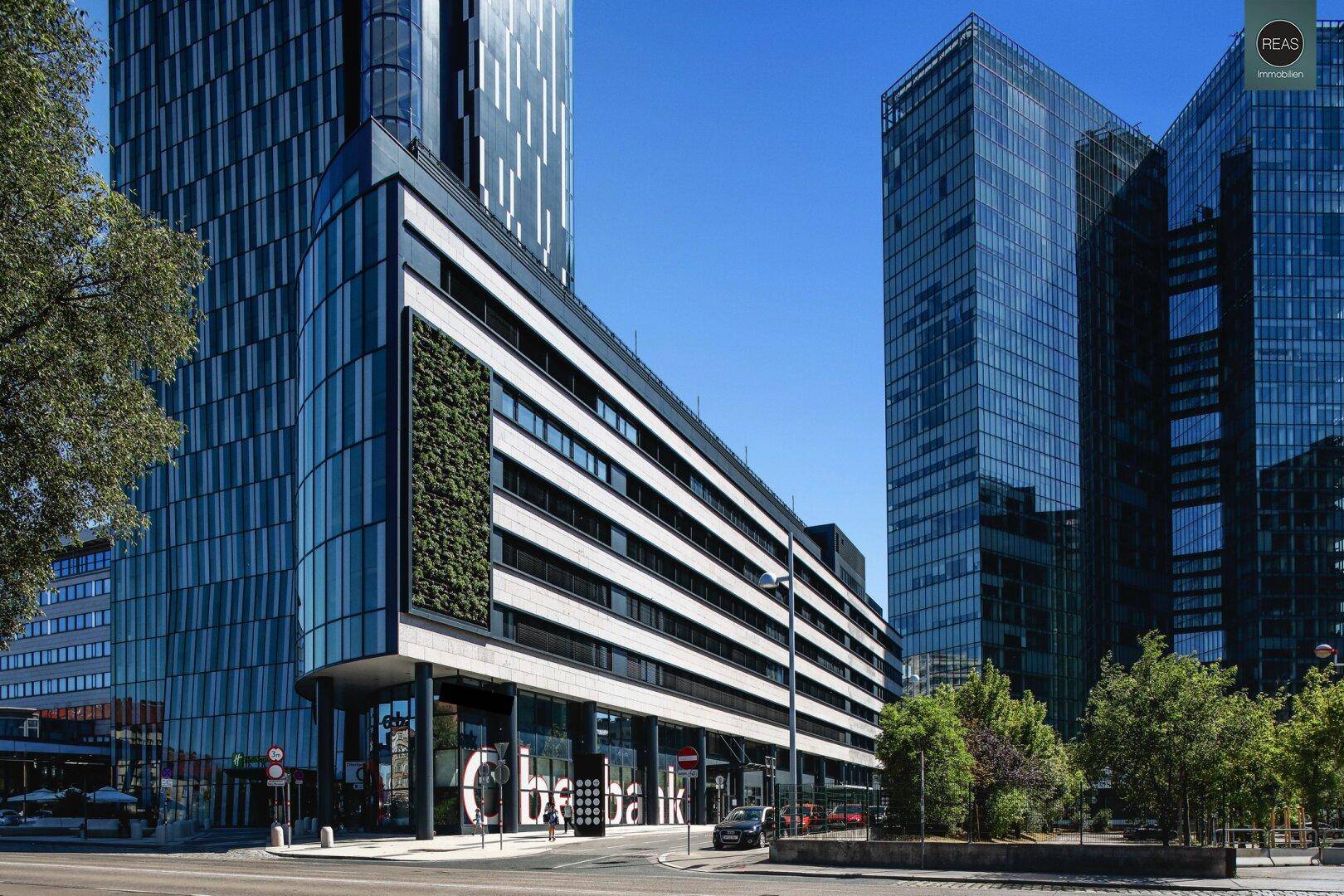 Moderne Bürogebäude mit Glasfassaden und vertikaler Begrünung unter blauem Himmel.