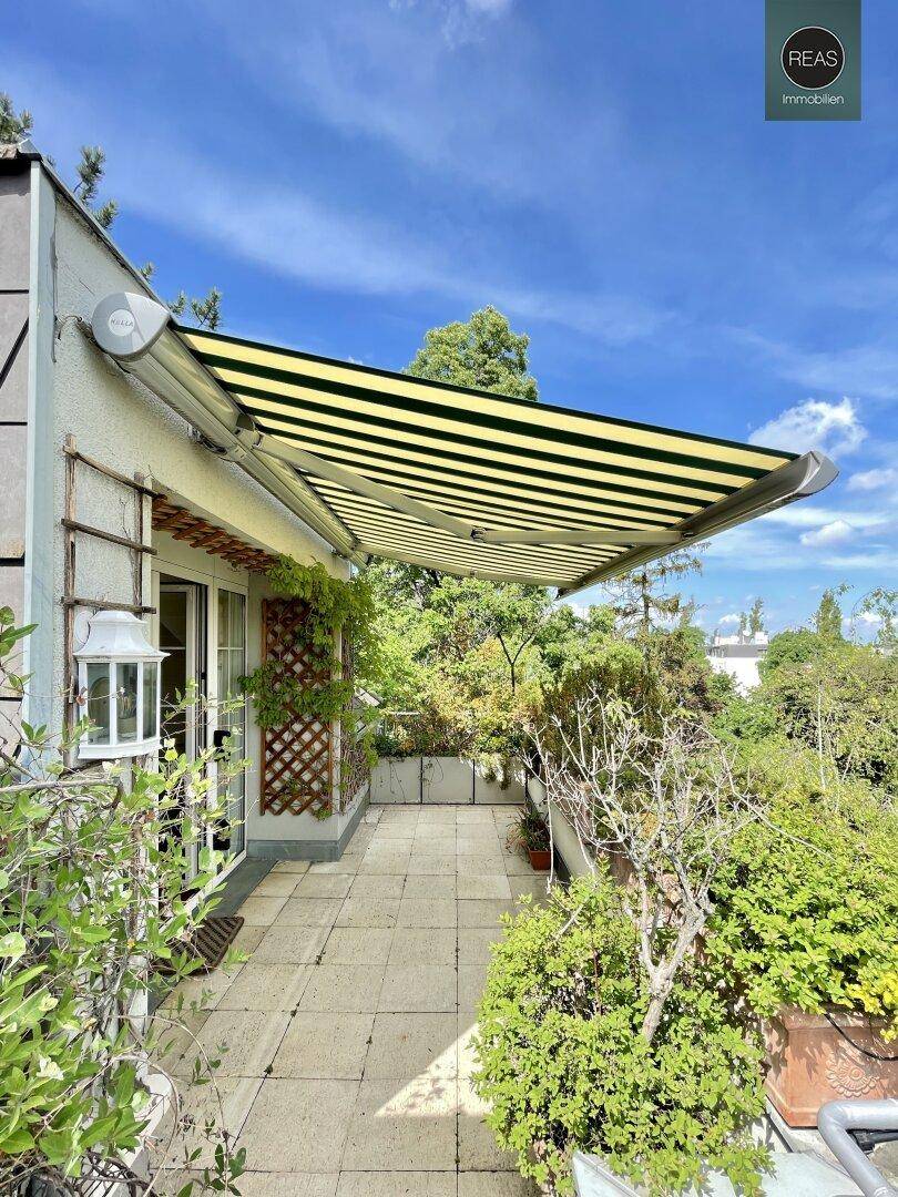 Geräumiger Balkon mit Markise, Fliesenboden und üppiger Bepflanzung, ideal zum Entspannen im Freien.