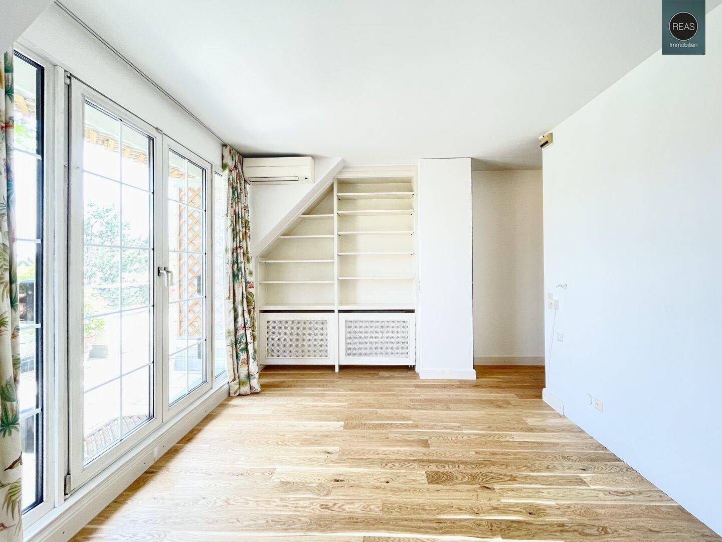 Geräumiges Schlafzimmer mit Holzboden, Einbauregalen und Zugang zur Terrasse.