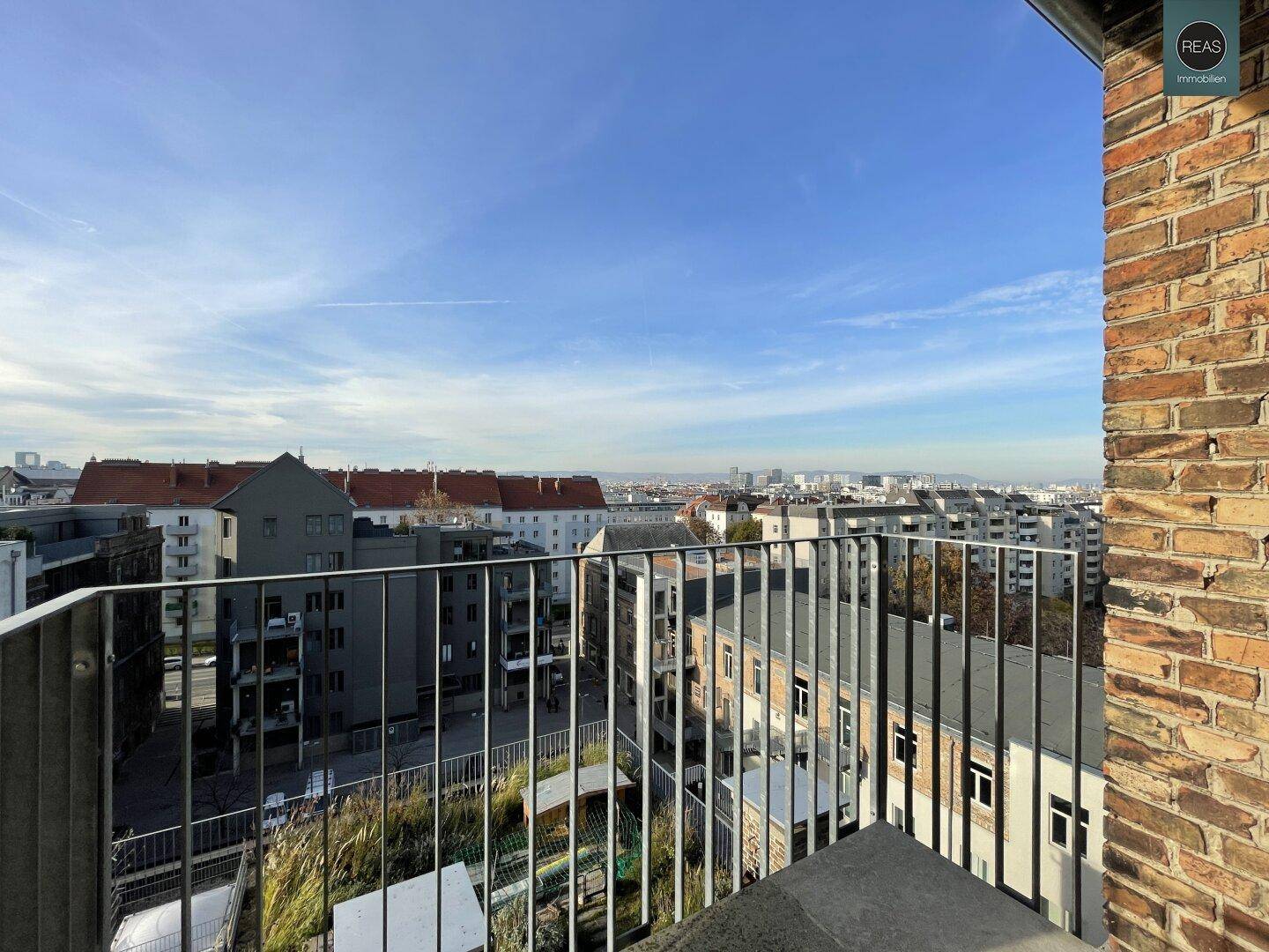 Balkon mit Metallgeländer bietet einen weiten Blick über die Stadt und umliegende Gebäude.