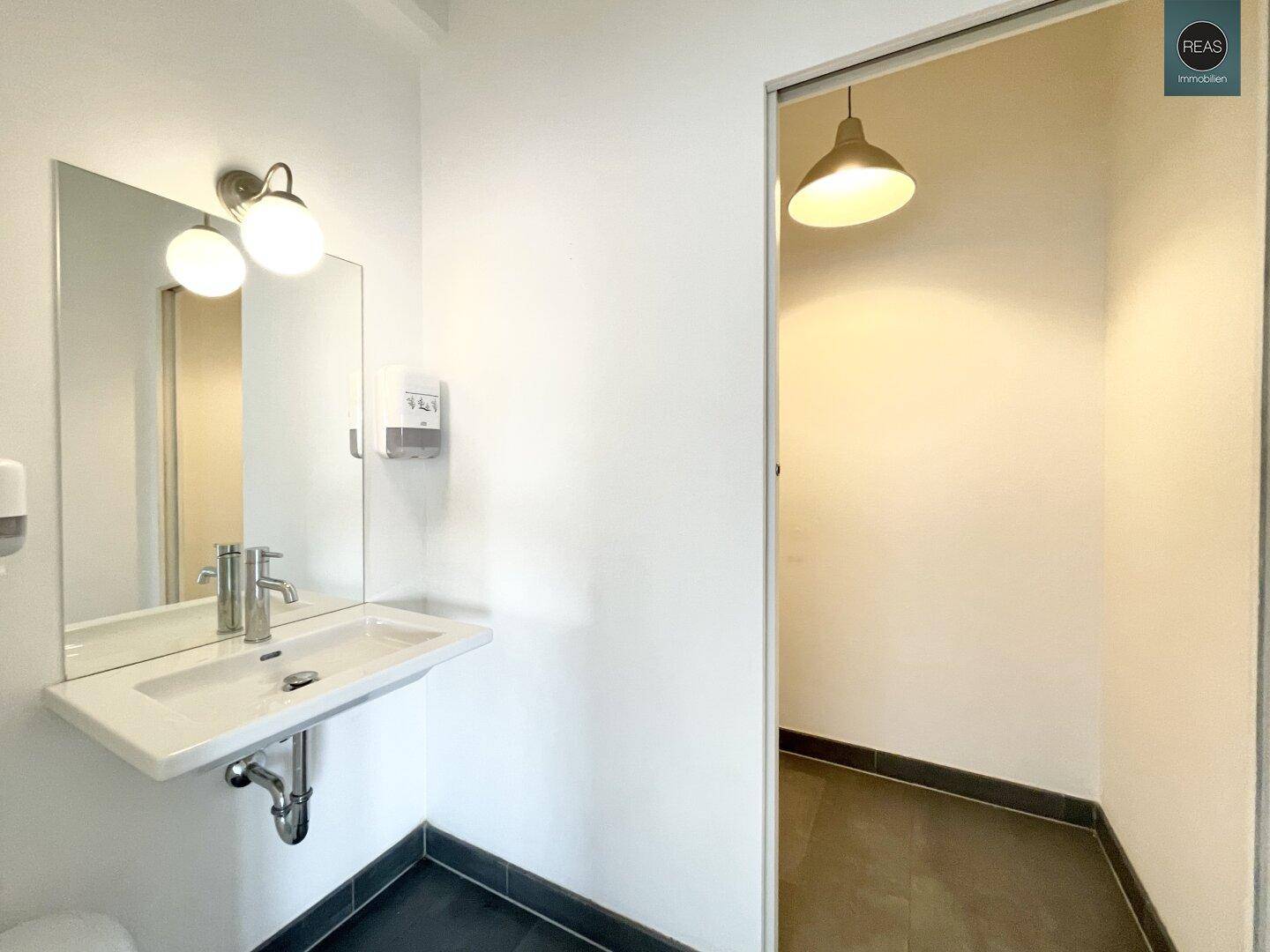 Modernes Gäste-WC mit Waschbecken und Spiegel, in schlichtem Design gehalten.