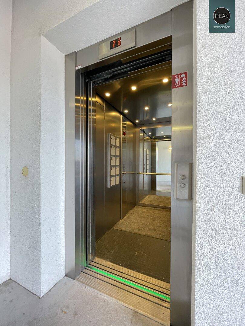 Moderner Aufzug mit Edelstahloberflächen und beleuchteter Kabine in einem Mehrfamilienhaus.