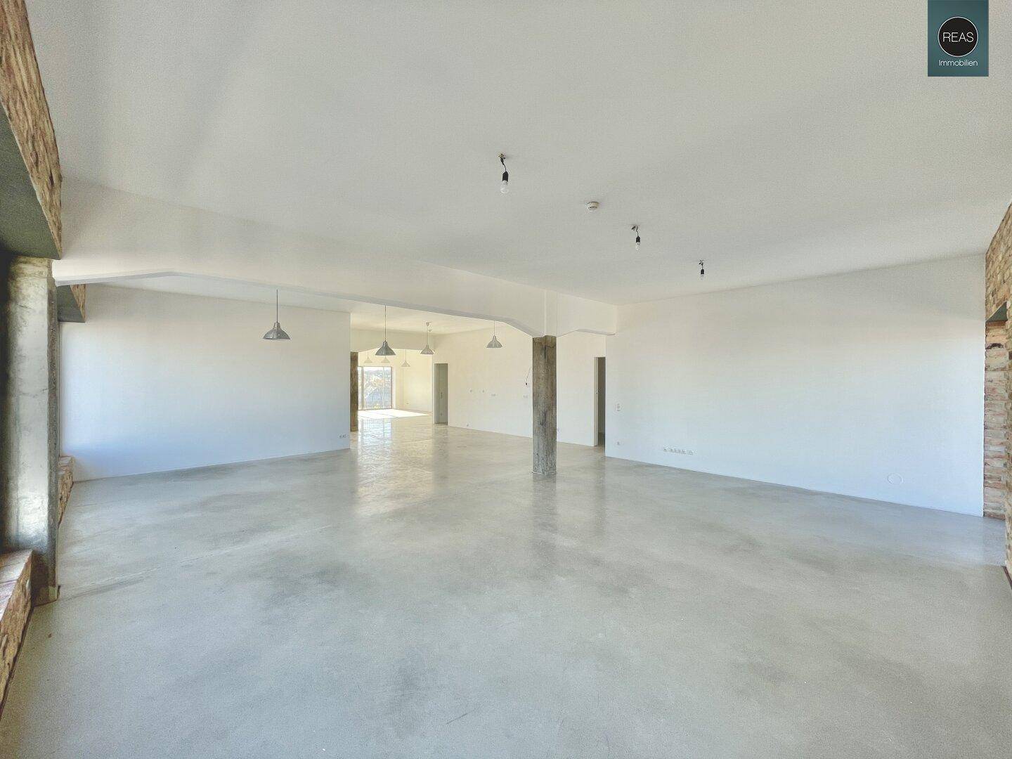 Geräumiger, leerer Büroraum mit Betonboden und weißen Wänden, bereit für individuelle Gestaltung.