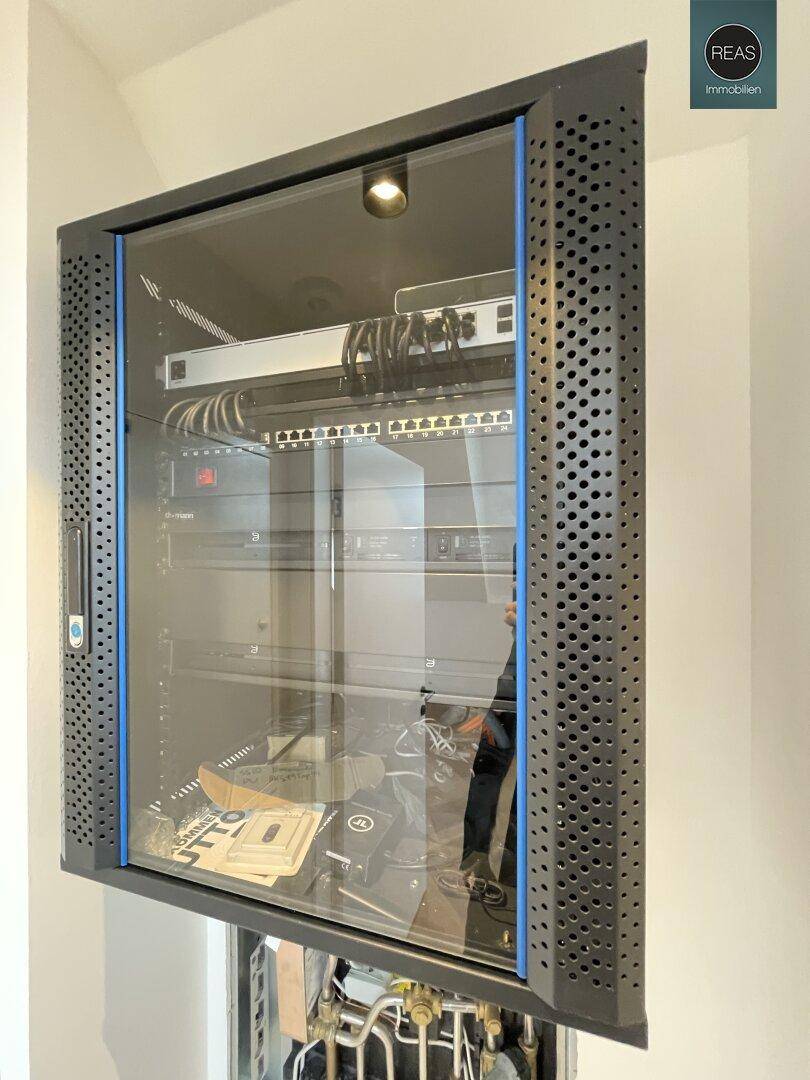 Server-Rack mit Netzwerkkomponenten und Verkabelung in einem Technikraum.