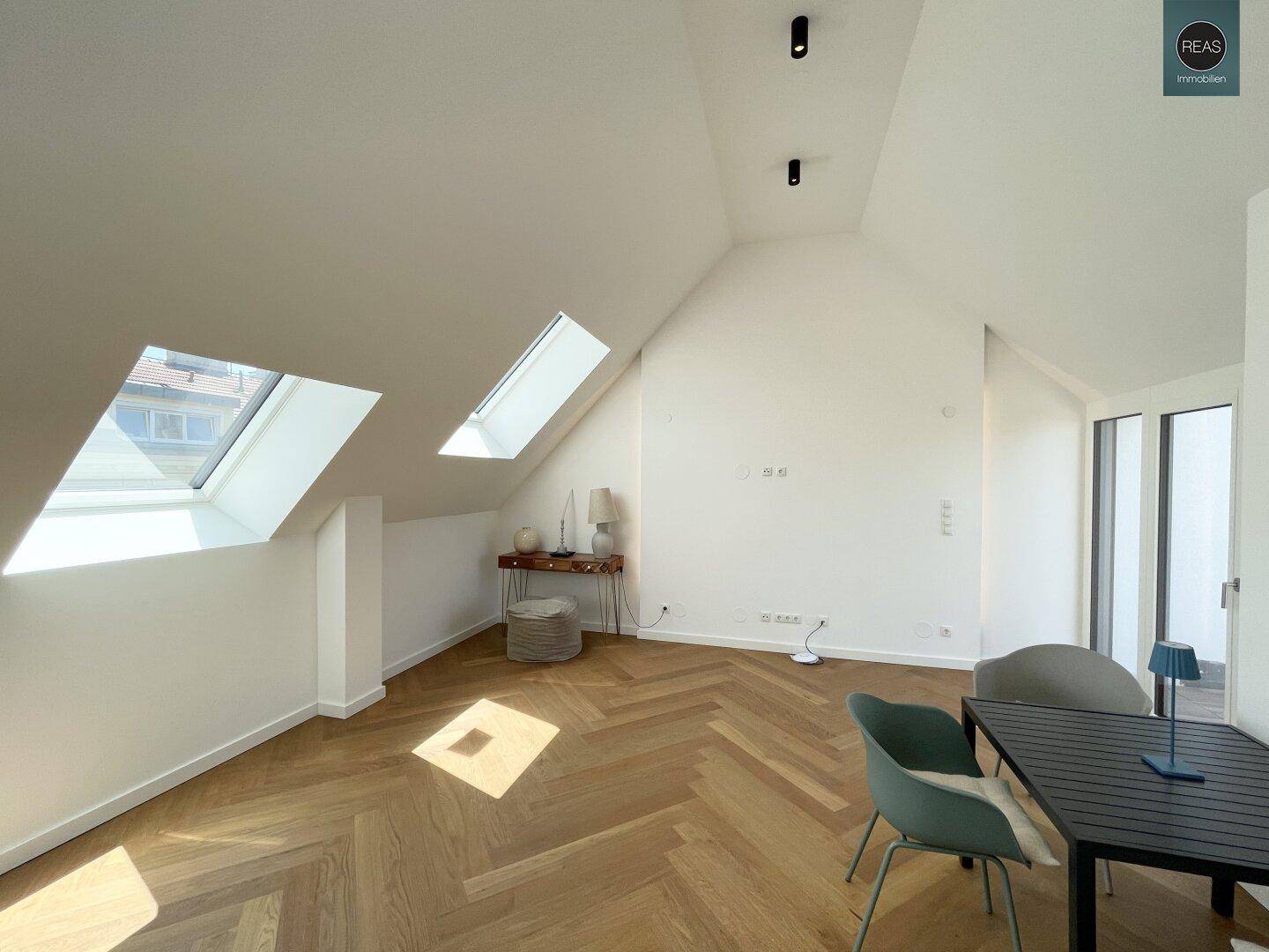 Dachgeschoss-Wohnbereich mit schrägen Wänden, Dachfenstern und modernem Parkettboden.
