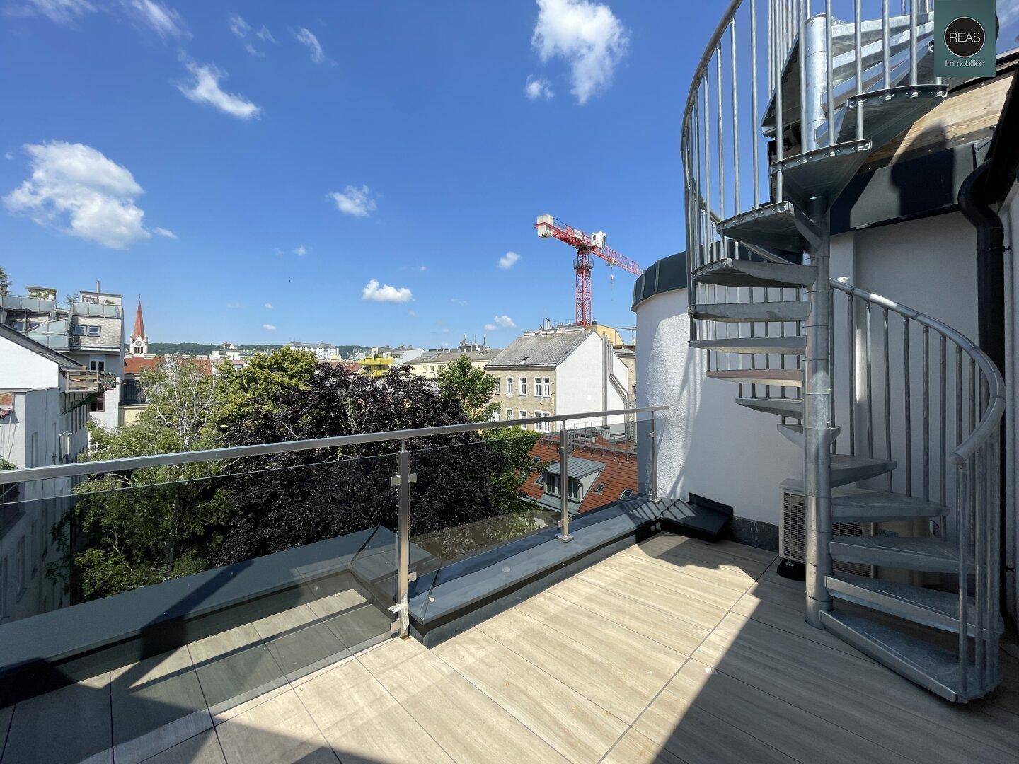 Dachterrasse mit Wendeltreppe und Panoramablick über die Stadt an einem sonnigen Tag.