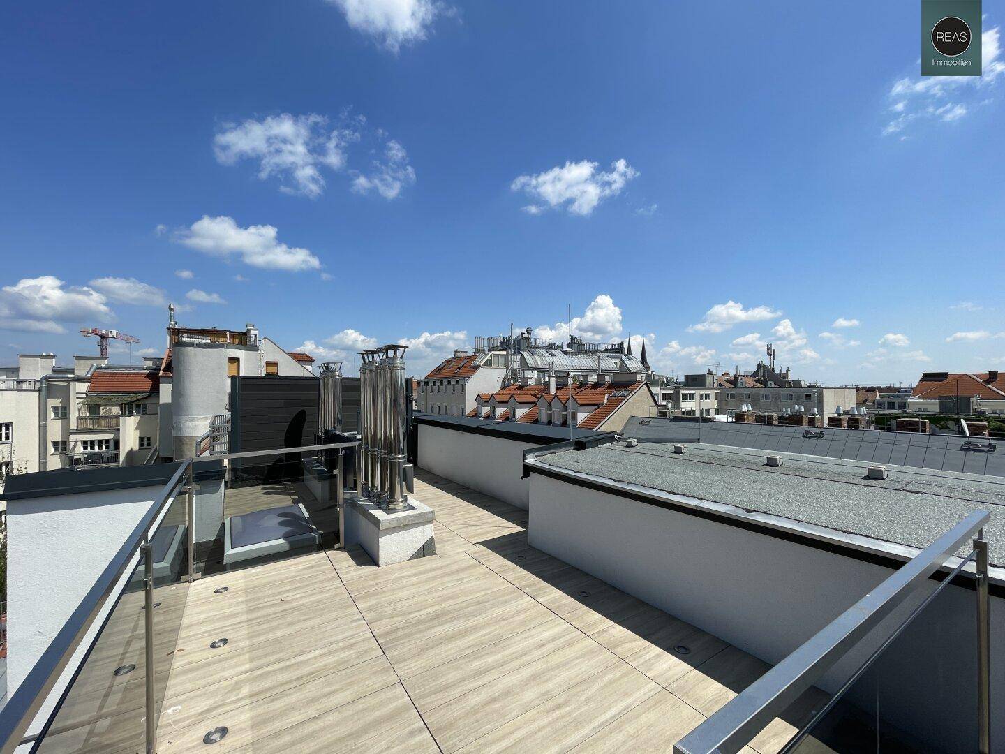 Geräumige Dachterrasse mit Fliesenboden und Blick auf die Dächer der Stadt.