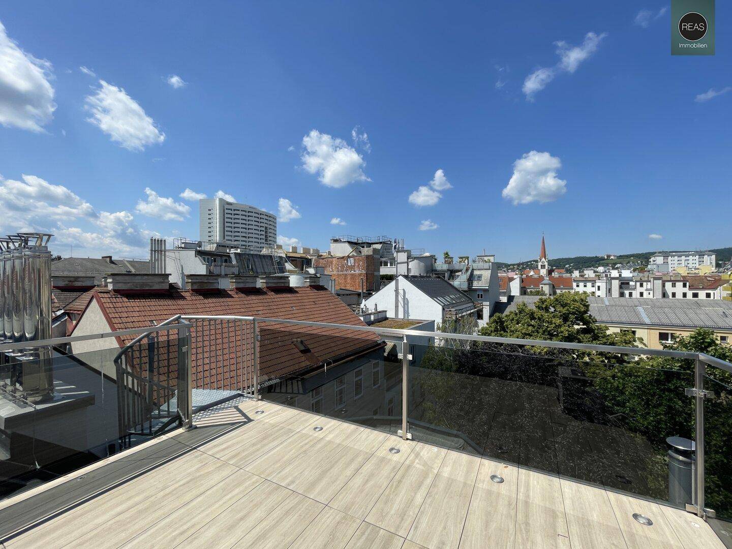 Weitläufige Dachterrasse mit Blick auf die umliegende Stadtarchitektur und den Himmel.