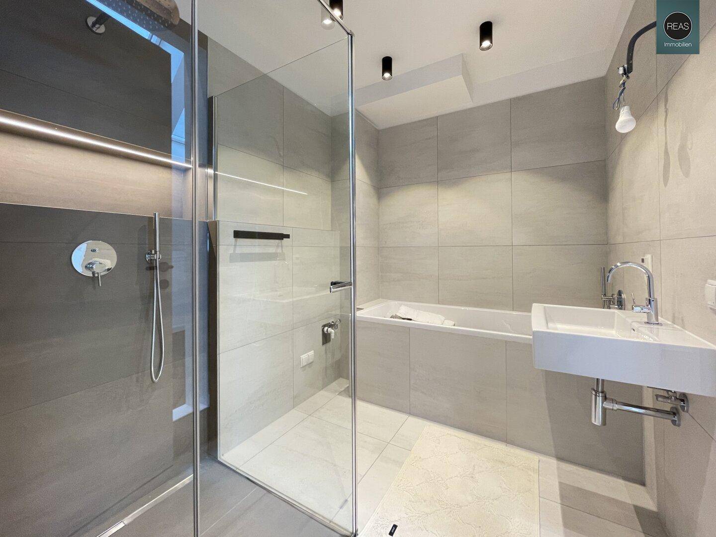 Modernes Badezimmer mit begehbarer Dusche, Badewanne und grauen Fliesen.