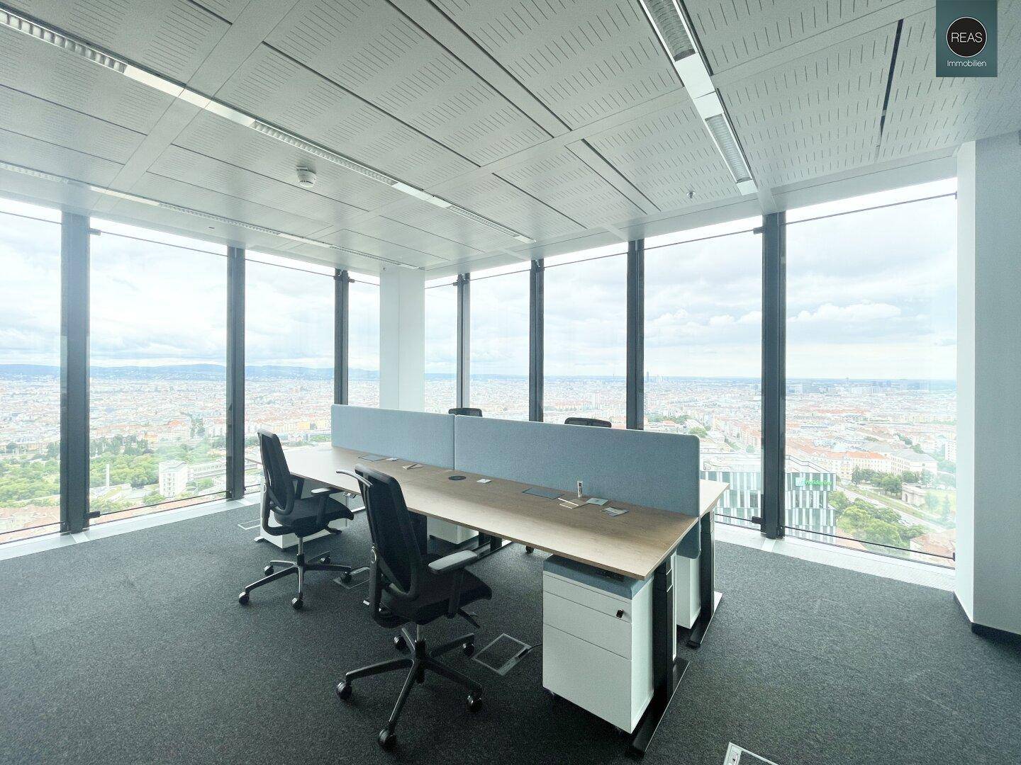 Offener Bürobereich mit mehreren Arbeitsplätzen und Trennwänden, bietet einen weiten Blick auf die Stadt.