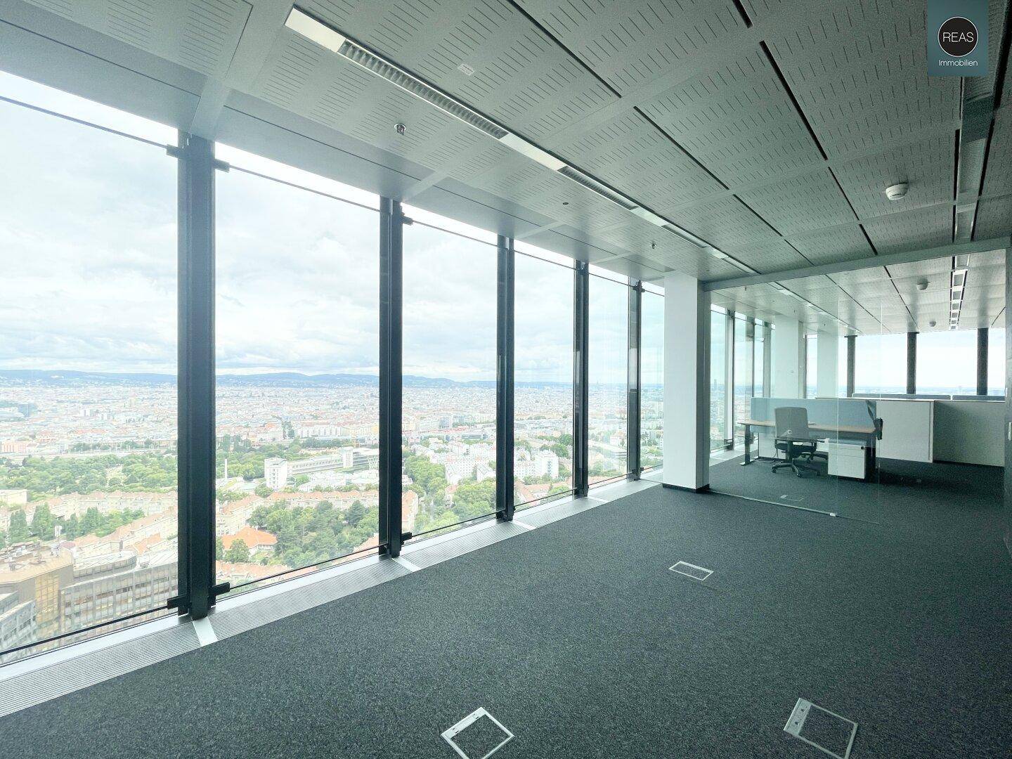 Geräumiger, leerer Bürobereich mit großen Fenstern, die einen weiten Blick über die Stadtlandschaft bieten.