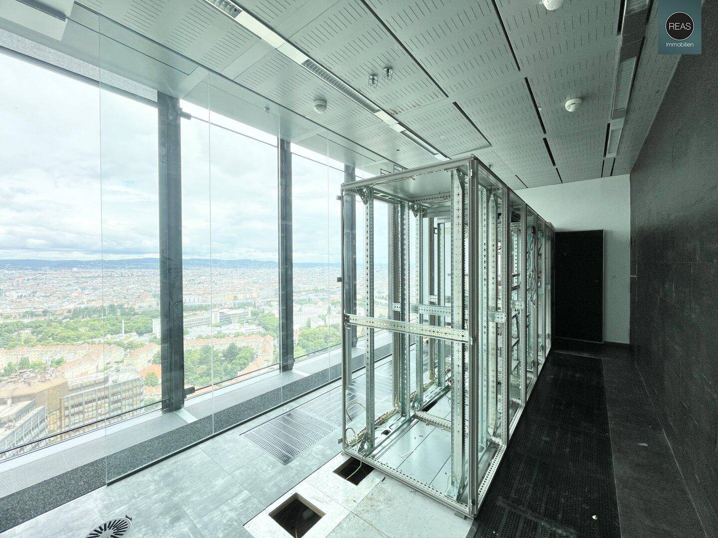 Technischer Raum mit Serverracks und großen Fenstern, die einen weiten Blick auf die Stadt bieten.