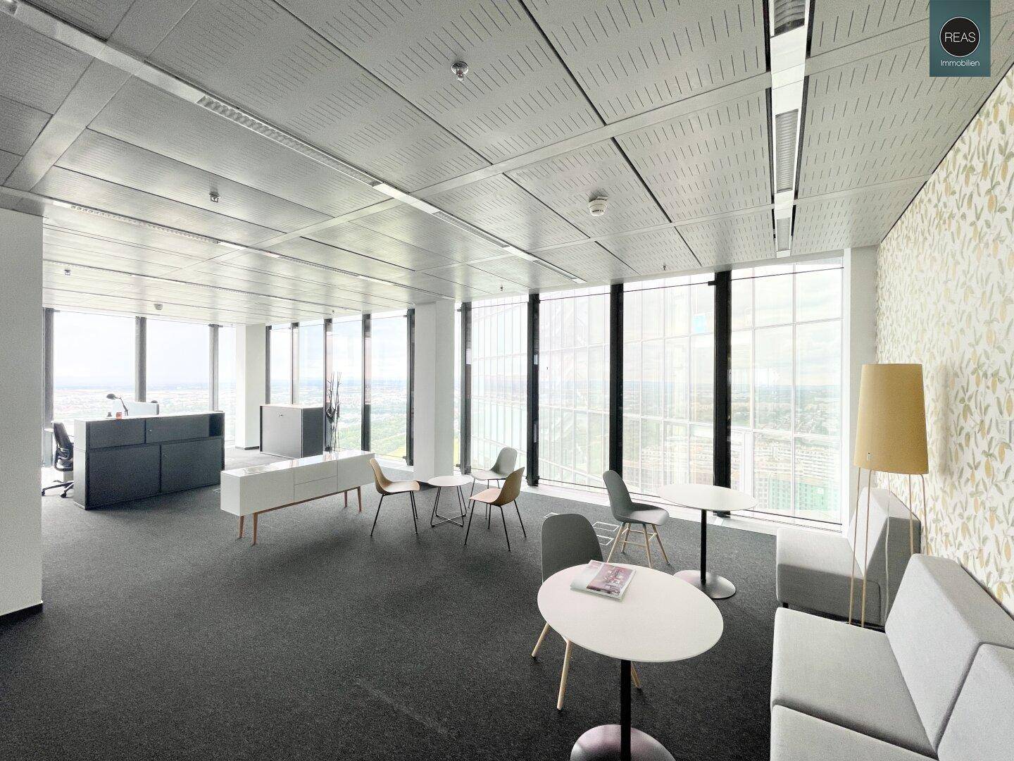 Moderner Bürobereich mit Sitzgelegenheiten und dekorativer Tapete, bietet einen weiten Blick auf die Umgebung.