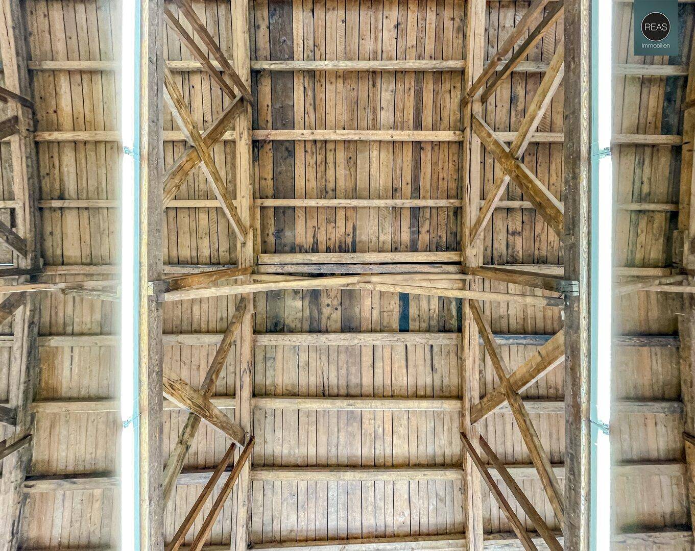 Detailansicht der robusten Holzbalkenkonstruktion der Decke, die den Raum prägt.