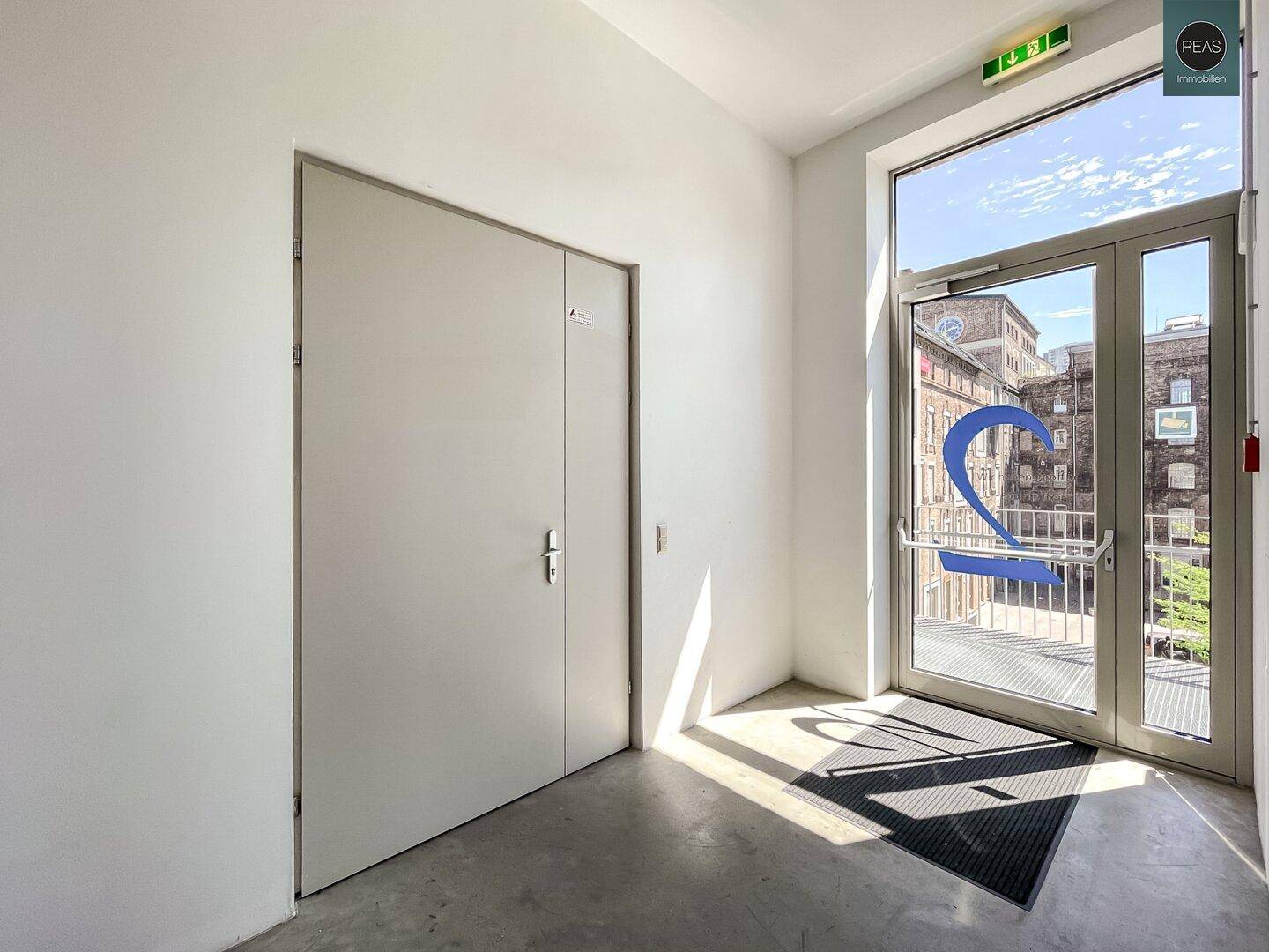 Heller Eingangsbereich mit großer Glastür, die viel Tageslicht hereinlässt.