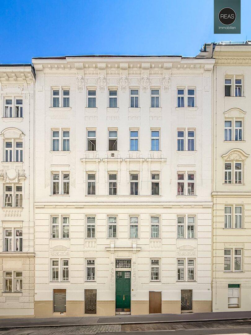 Prächtige Altbaufassade mit vielen Fenstern und einer grünen Eingangstür, gut erhalten.