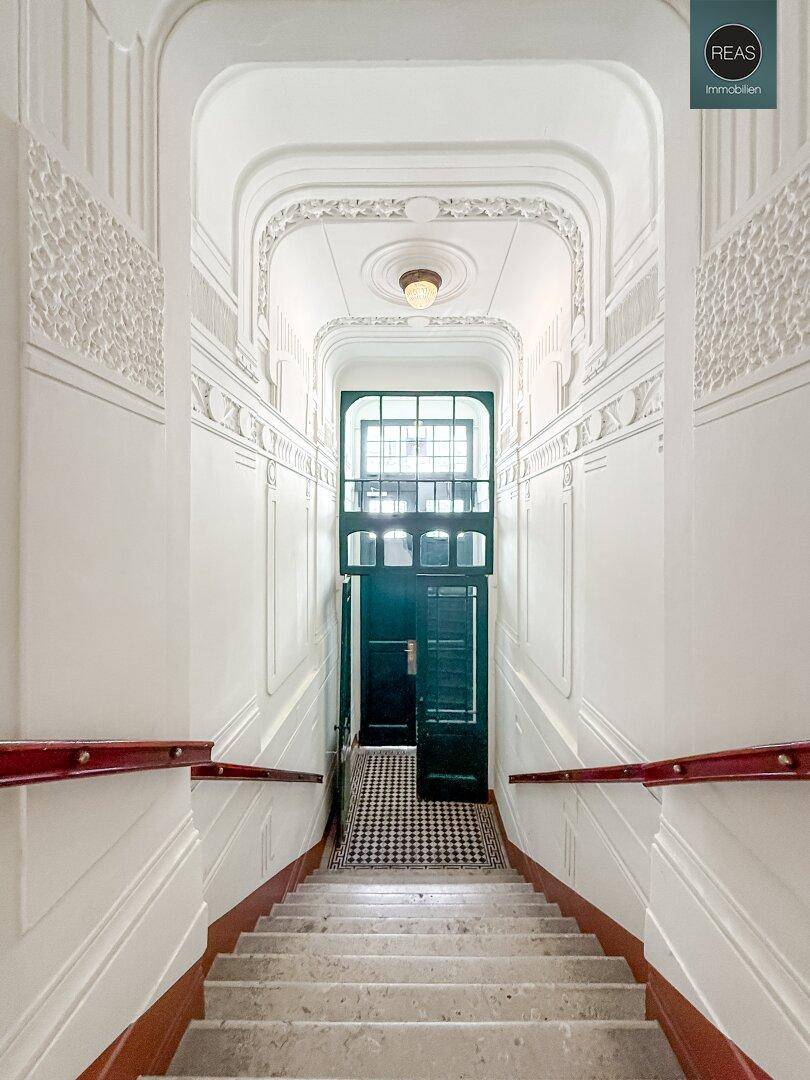 Elegantes Treppenhaus mit Marmorstufen, verzierten Geländern und hohen Decken.